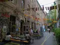 En livlig innergård i Prenzlauer Berg, Berlin, med väggmålningar, ljusslingor och sittplatser utomhus.