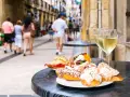 Tapas och vin på en uteservering i San Sebastián. Folk promenerar förbi på den livliga gatan.