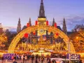 En magisk julmarknad i Wien, med Rådhuset i bakgrunden, gnistrar av tusentals ljus. En båge av gyllene ljusslingor välkomnar besökare till den livliga julmarknaden.