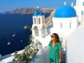 Kvinna i grön klänning njuter av utsikten över Santorini. Perfekt för dig som söker **resa ensam tips** för en oförglömlig grekisk upplevelse.