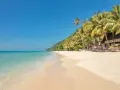 En strand på Ko Chang med palmer, turkost vatten och en byggnad.