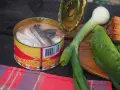 En burk med sill, en klassisk del av **comida tipica sueca**, ligger bredvid färska grönsaker och bröd.