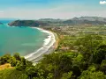 Vacker kustlinje med turkost hav, vågor som slår mot en sandstrand och frodig grönska som omger en stad. En dröm om en costa rica strand.