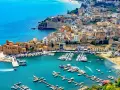 En charmig hamn i Palermo, Sicilien, med färgglada hus och många båtar i det turkosa vattnet.