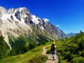 En person vandrar på en stig i Chamonix med majestätiska berg och en glaciär i bakgrunden.