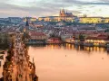 En livlig kväll på Karlsbron i Prag, med tusentals besökare som promenerar mot slottet. En perfekt vy för den som tar tåg till Prag.