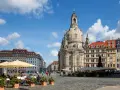 En solig dag i Dresden, Tyskland. Folk sitter vid kafébord på ett torg framför den imponerande Frauenkirche.