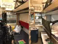 En kvinna sitter i en liggvagn SJ. Bredvid henne finns bagage och en bädd.