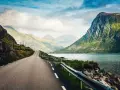 Väg som slingrar sig genom dramatiskt landskap med berg och fjord. En drömresa till Lofoten från Stockholm.