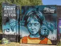 En färgstark graffiti i Stockholm med en flicka och en apa. Texten "WE NEED TO GET ANGRY AND TRANSFORM THAT ANGER INTO ACTION" syns tydligt.