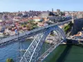 Imponerande bro över Dourofloden i norra Portugal, med en stad full av färgglada hus och kyrkor i bakgrunden.