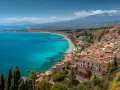 Vacker kustvy med turkost hav, en strand och en stad vid foten av Etna. Perfekt för din sicilien reseguide.