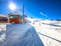 Ett snötäckt tåg i Schweiz, redo att transportera skidåkare uppför berget under en strålande solig dag.
