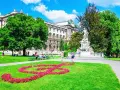 En vacker sommardag i Wien. En blomsterformation i form av en fiolnyckel lyser upp gräsmattan framför Mozarts staty. Ett perfekt ställe att se i Wien.