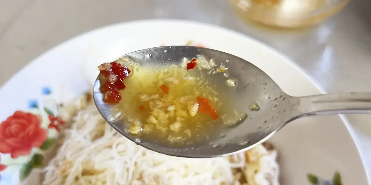 En sked med kryddig sås med vitlök och chili, redo att förhöja smaken på kambodjansk mat.