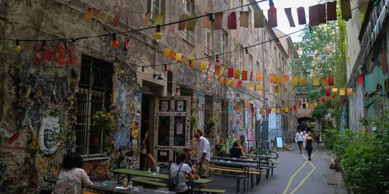 En livlig innergård i Prenzlauer Berg, Berlin, med väggmålningar, ljusslingor och sittplatser utomhus.