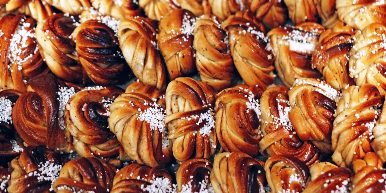 En stor bricka med gyllenbruna kanelbullar, en svensk specialitet, toppade med pärlsocker.