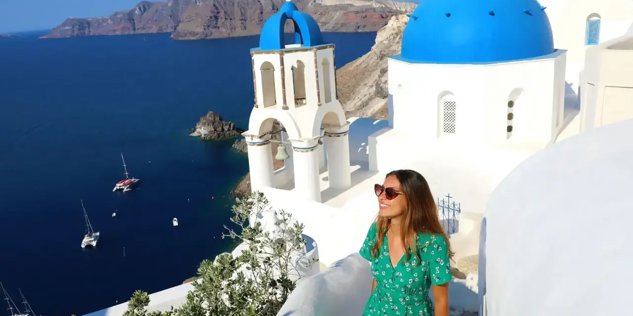 Kvinna i grön klänning njuter av utsikten över Santorini. Perfekt för dig som söker **resa ensam tips** för en oförglömlig grekisk upplevelse.