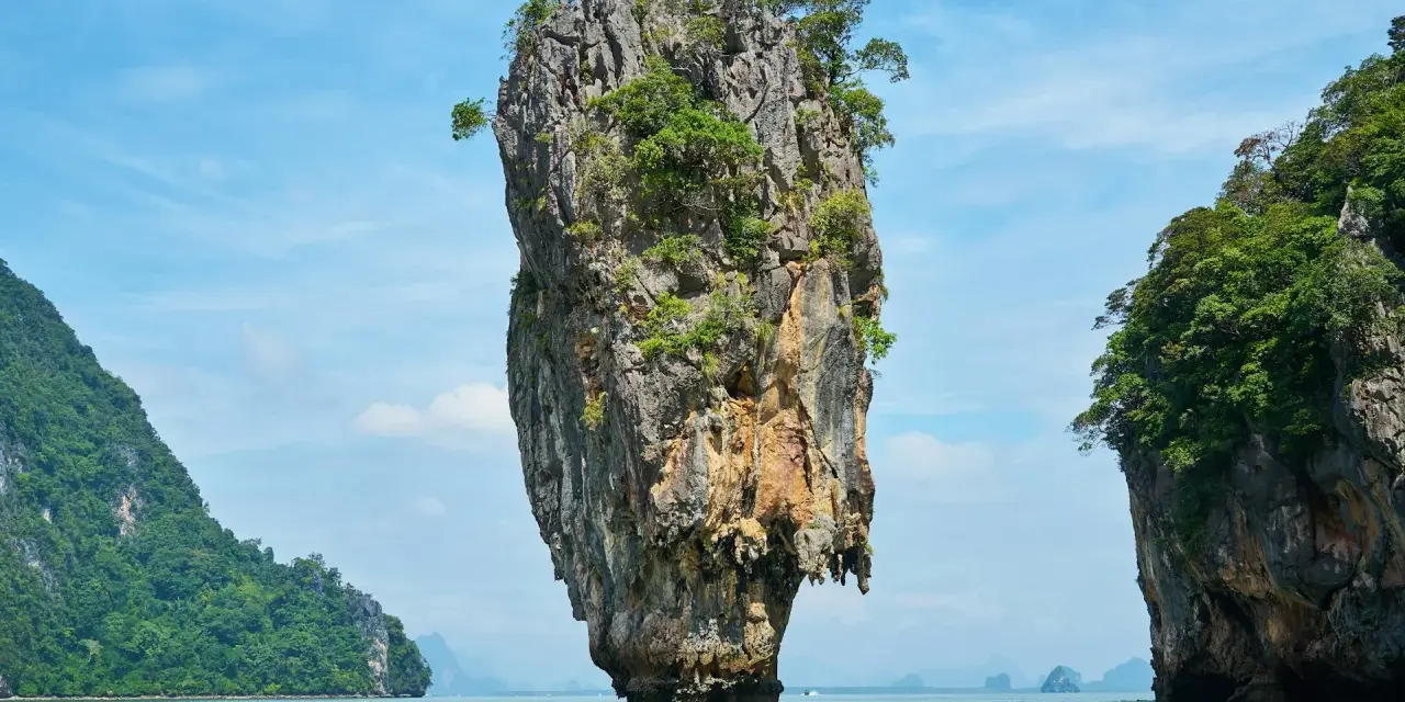 James Bond Island, en ikonisk kalkstensklippa som reser sig ur havet, omgiven av frodiga öar under en klarblå himmel.