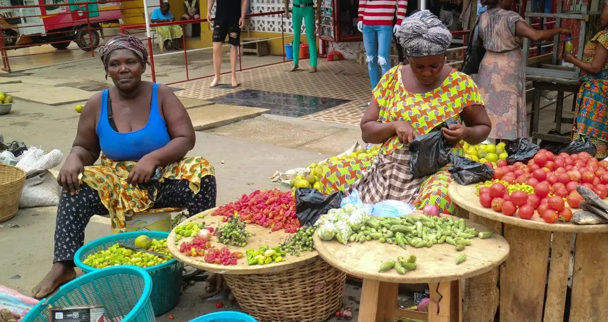 Kvinnor säljer färska grönsaker och frukter på en marknad. En del av deras resa till Ghana.