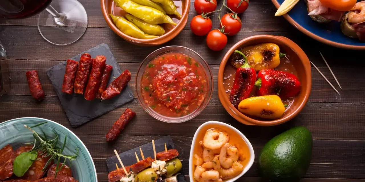 En härlig samling portugal mat: charkuterier, räkor, oliver, paprika och tomater, perfekt för en tapasbuffé.