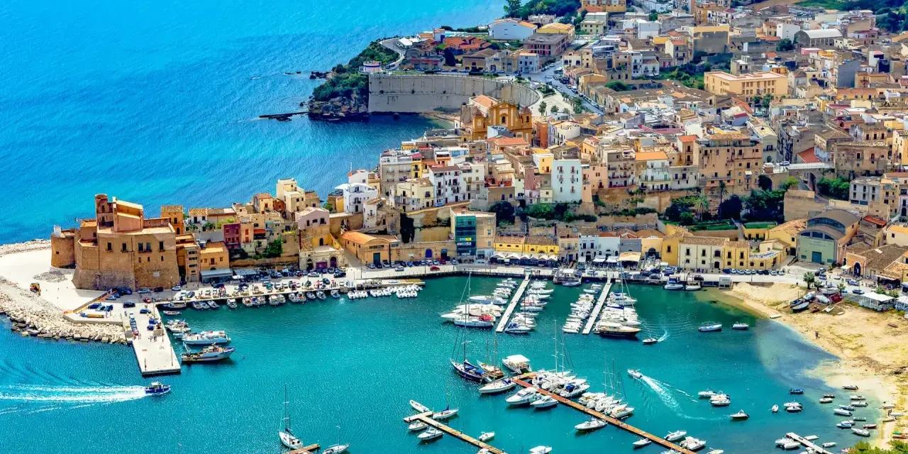En charmig hamn i Palermo, Sicilien, med färgglada hus och många båtar i det turkosa vattnet.