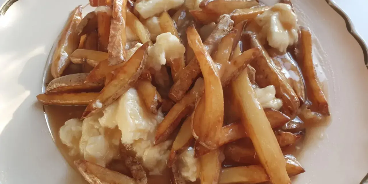 En tallrik med kanadas nationalrätt, poutine: friterade pommes frites, ostbitar och sås.