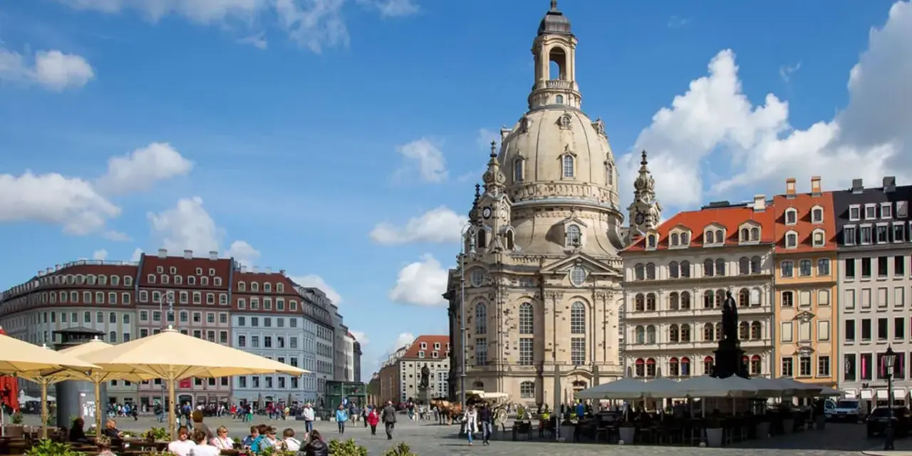 En solig dag i Dresden, Tyskland. Folk sitter vid kafébord på ett torg framför den imponerande Frauenkirche.