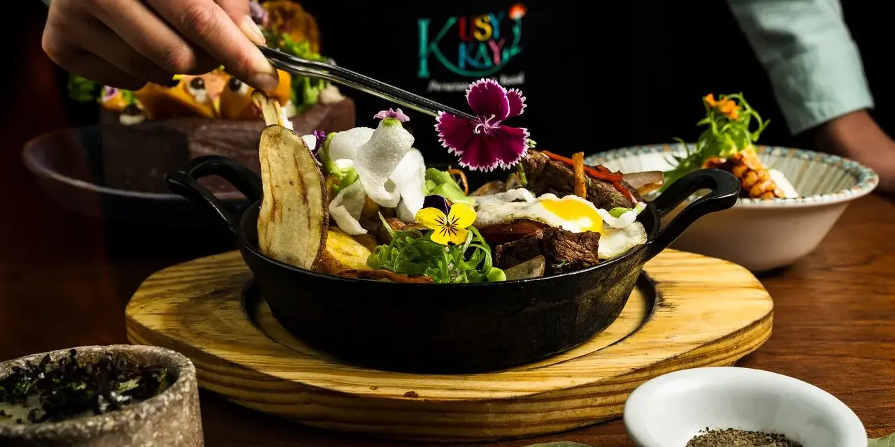 En hand dekorerar en mustig gryta med kött, potatis och blommor. En utsökt rätt som påminner om kanadensiskt kök.