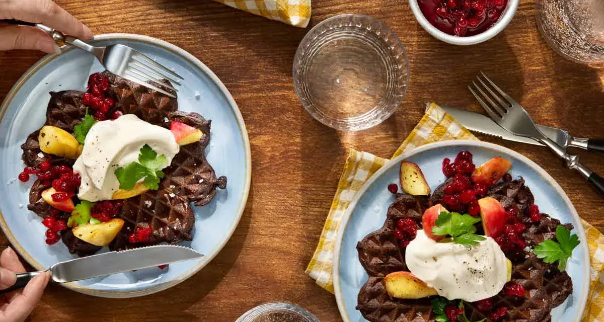Mörka våfflor med lingon, äpple och grädde – en klassisk svensk frukost.