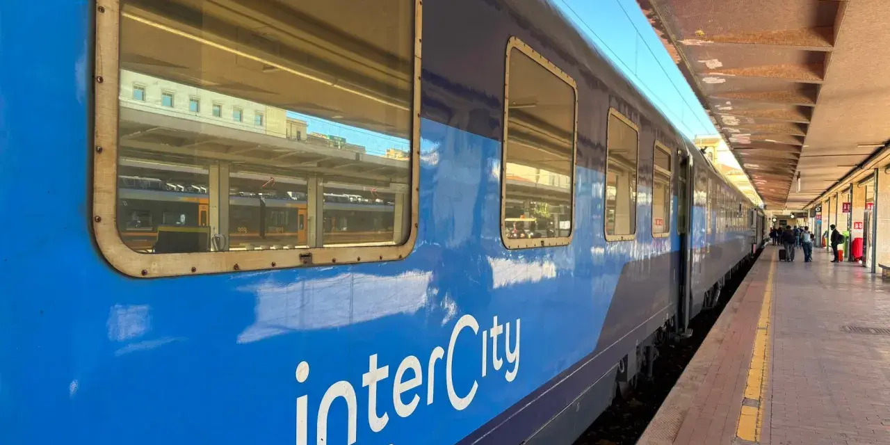 Blått InterCity-tåg står vid perrongen, redo för en resa till Sicilien.
