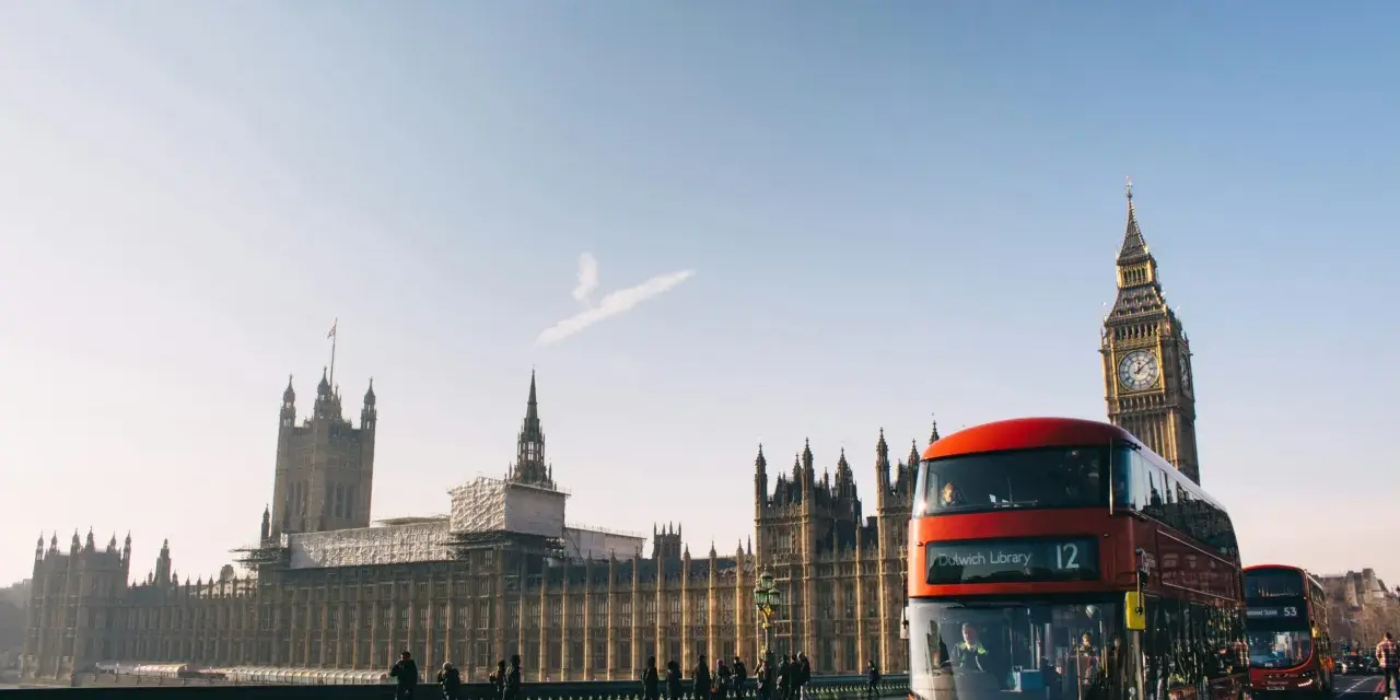En röd dubbeldäckare passerar Big Ben och Houses of Parliament. En perfekt dag för en **turista i London**.