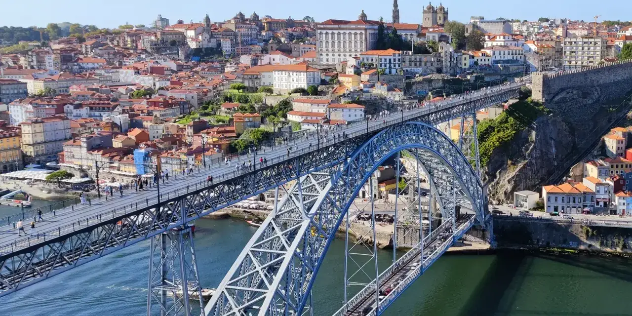 Imponerande bro över Dourofloden i norra Portugal, med en stad full av färgglada hus och kyrkor i bakgrunden.