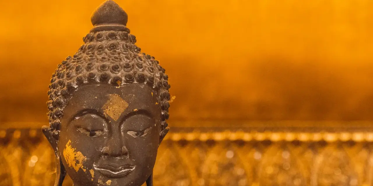 Buddhas ansikte med guldfolierester, en påminnelse om lugn under regnperioden i Asien.