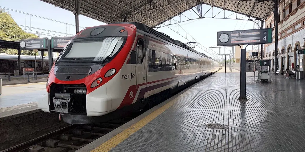Ett modernt rött och vitt Renfe-tåg står redo på perrongen. Kanske är det dags för ett tåg till Spanien?