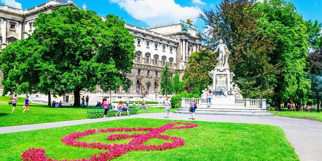 En vacker sommardag i Wien. En blomsterformation i form av en fiolnyckel lyser upp gräsmattan framför Mozarts staty. Ett perfekt ställe att se i Wien.