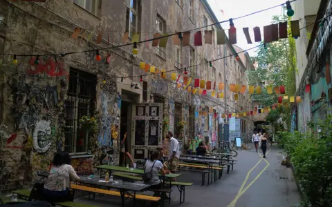 En livlig innergård i Prenzlauer Berg, Berlin, med väggmålningar, ljusslingor och sittplatser utomhus.