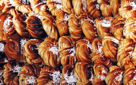 En stor bricka med gyllenbruna kanelbullar, en svensk specialitet, toppade med pärlsocker.