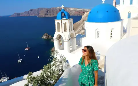 Kvinna i grön klänning njuter av utsikten över Santorini. Perfekt för dig som söker **resa ensam tips** för en oförglömlig grekisk upplevelse.
