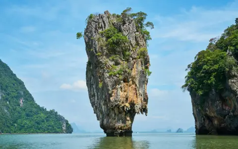 James Bond Island, en ikonisk kalkstensklippa som reser sig ur havet, omgiven av frodiga öar under en klarblå himmel.