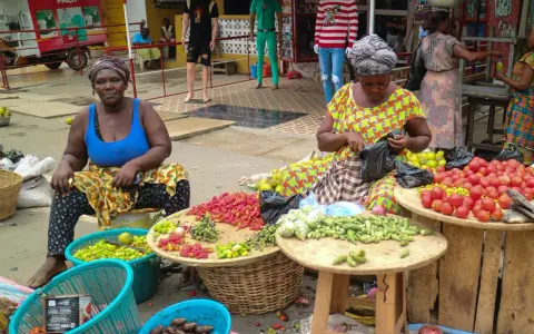 Kvinnor säljer färska grönsaker och frukter på en marknad. En del av deras resa till Ghana.