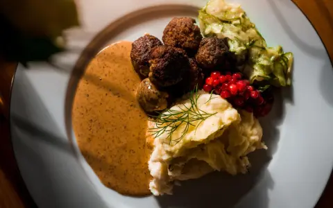 Klassiska svenska rätter: köttbullar med krämig sås, potatismos, lingon och pressgurka.