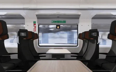 Interiör i ett modernt tåg med bekväma säten och fällbara bord. Nya nattåg erbjuder en bekväm resa genom det snöiga landskapet.