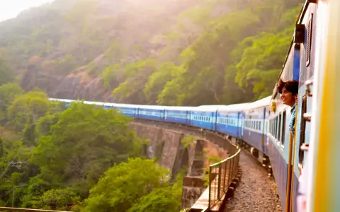Ung man ler från tågfönstret på en resa genom grönskande landskap. Bra interrail tips för äventyrliga resor!