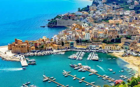 En charmig hamn i Palermo, Sicilien, med färgglada hus och många båtar i det turkosa vattnet.