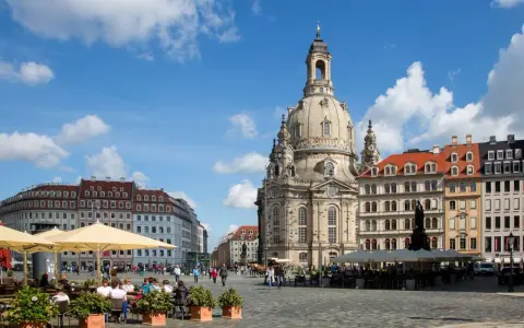 En solig dag i Dresden, Tyskland. Folk sitter vid kafébord på ett torg framför den imponerande Frauenkirche.