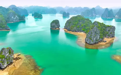 Vackra kalkstensklippor reser sig ur turkost vatten i Halongbukten, Vietnam. Priser för en resa hit är väl värda upplevelsen.