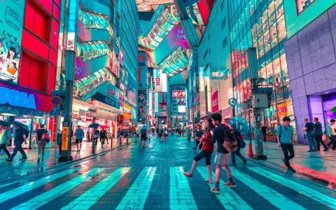 Neonbelyst gata i Tokyo, perfekt för din tokyo reseguide. Människor promenerar under paraplyer i regnet bland blinkande skyltar.
