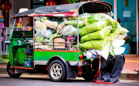 Grön tuk tuk thai lastad med grönsaker, redo för leverans.
