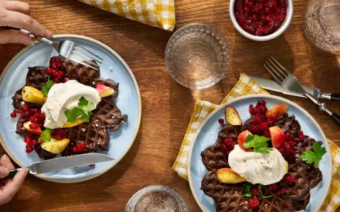 Mörka våfflor med lingon, äpple och grädde – en klassisk svensk frukost.